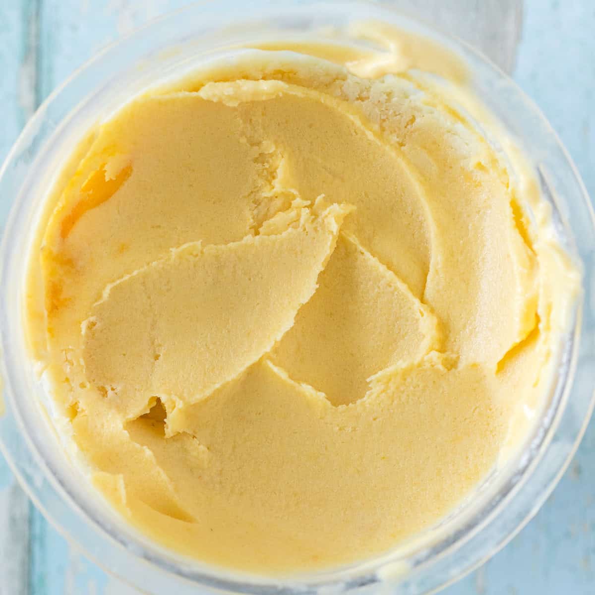 A close-up, top view of creamy orange ninja creami peach ice cream in a container.